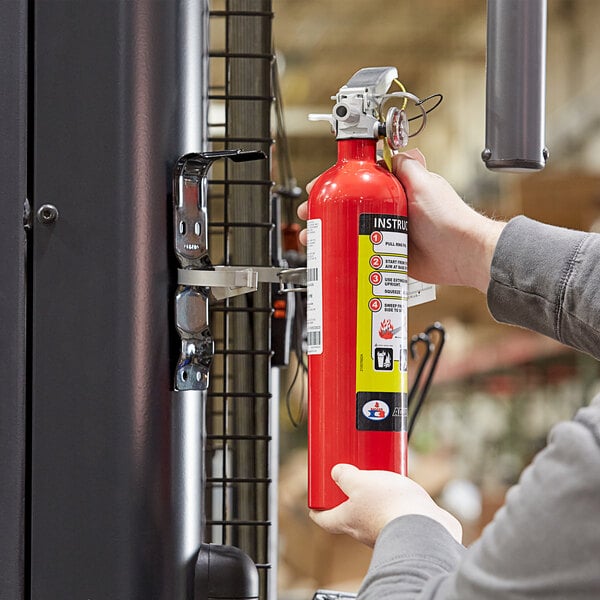 A person holding a Badger Advantage ABC fire extinguisher.