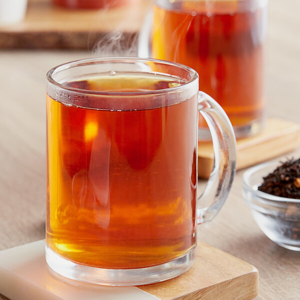 A glass mug of Davidson's Organic Cinnamon Apple loose leaf tea with steam coming out.