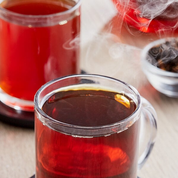 A close-up of a glass cup with Davidson's Organic Spiced Peach Loose Leaf Tea and smoke.