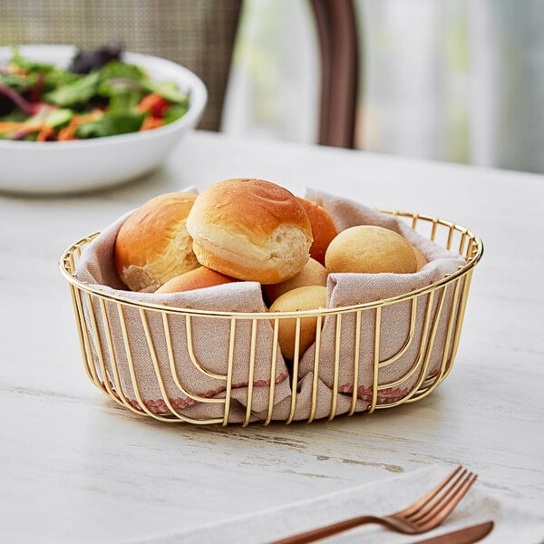 An Acopa gold wire basket filled with bread rolls.