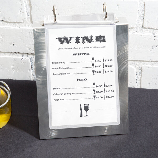 An Alumitique aluminum menu tent with a swirl finish on a table with wine glasses and a glass of wine.