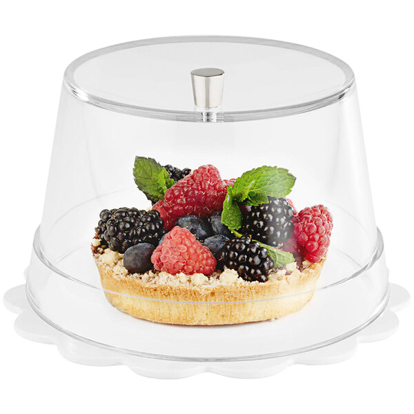 A dessert with berries inside of a clear plastic cover with a silver knob.