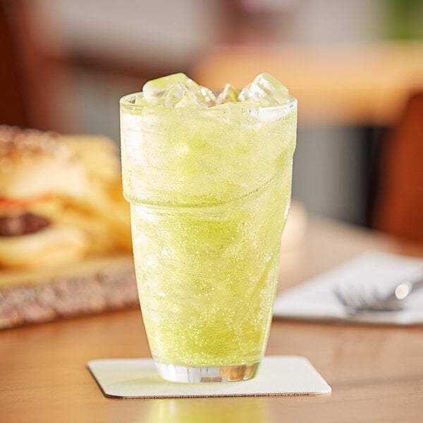 A glass of green Mountain Dew soda with ice on a table.