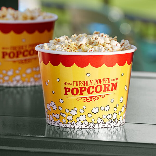 Two Carnival King popcorn buckets filled with popcorn on a table.