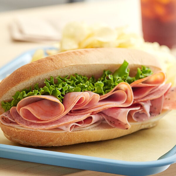 A sandwich with Kunzler Italian deli meats and lettuce on a tray.