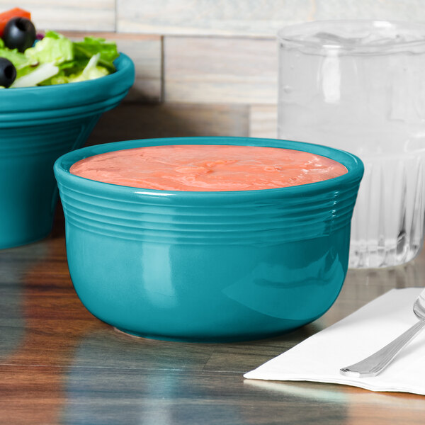 A turquoise Fiesta Gusto Bowl filled with soup on a table.