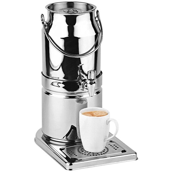A silver stainless steel APS Top Fresh milk/beverage dispenser on a stand with a white cup of brown liquid on top.