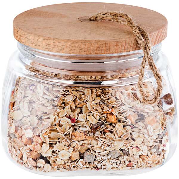 An APS Woody square glass jar filled with granola and nuts with a wooden lid.