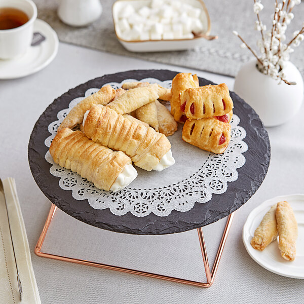 A table in a bakery with a Lace Normandy Doily under a plate of pastries and a cup of tea.