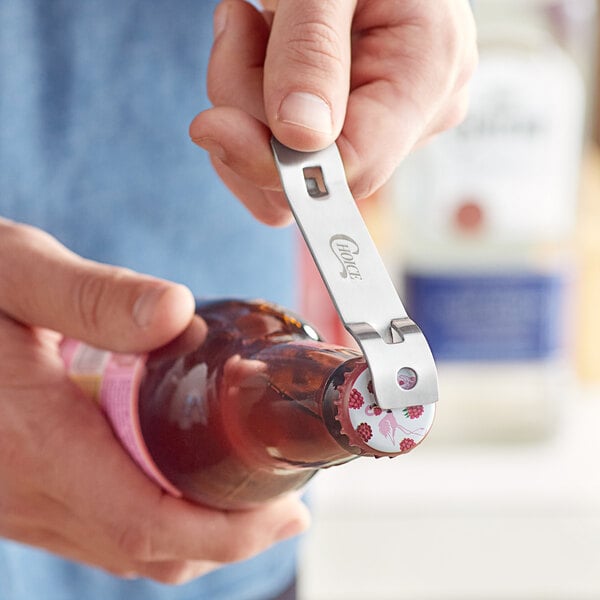 A hand using a Choice Church Key bottle opener to open a bottle of beer.