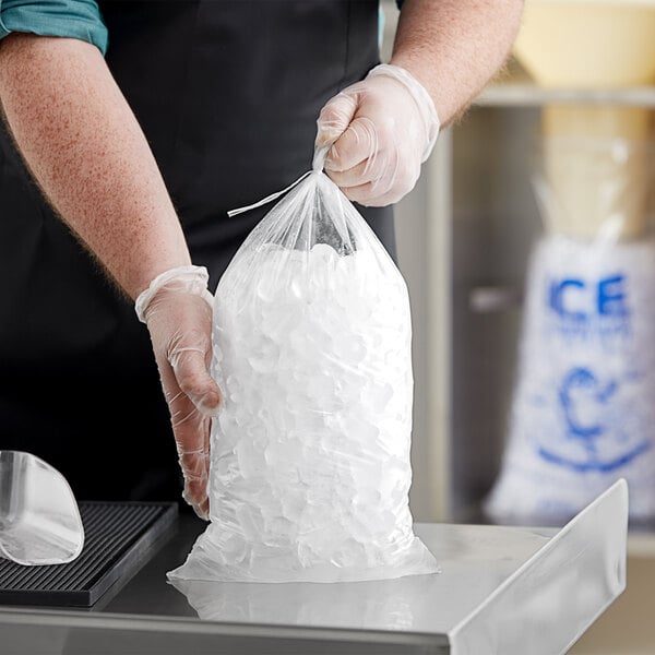 A person in gloves holding a Choice clear plastic ice bag full of ice.