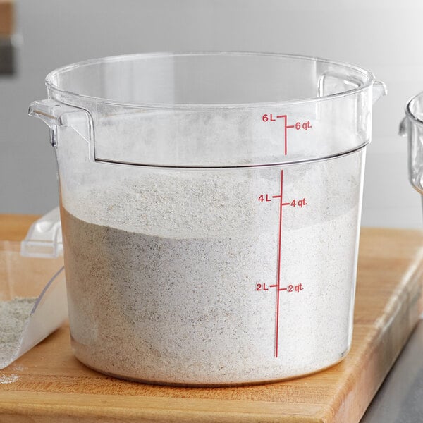 A measuring cup with white powder in it inside a Cambro round food storage container.