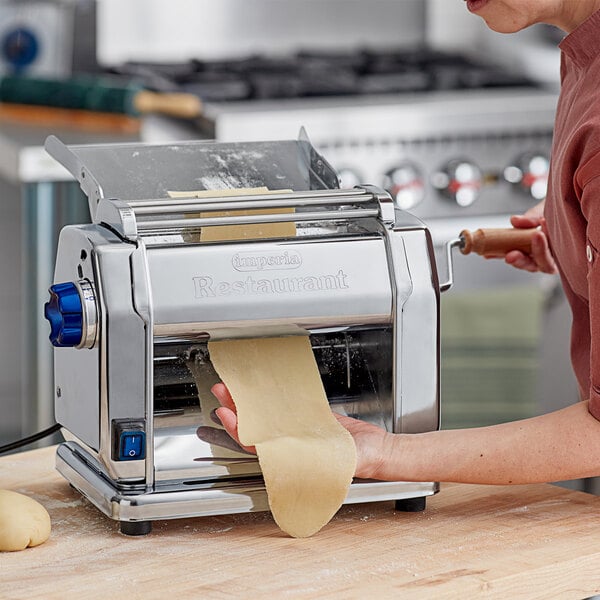 A woman using an Imperia electric pasta machine to roll out dough.