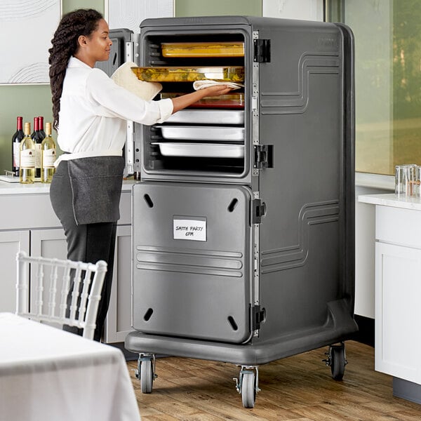 A woman using a Cambro Pro Cart Ultra to store food in a metal container.