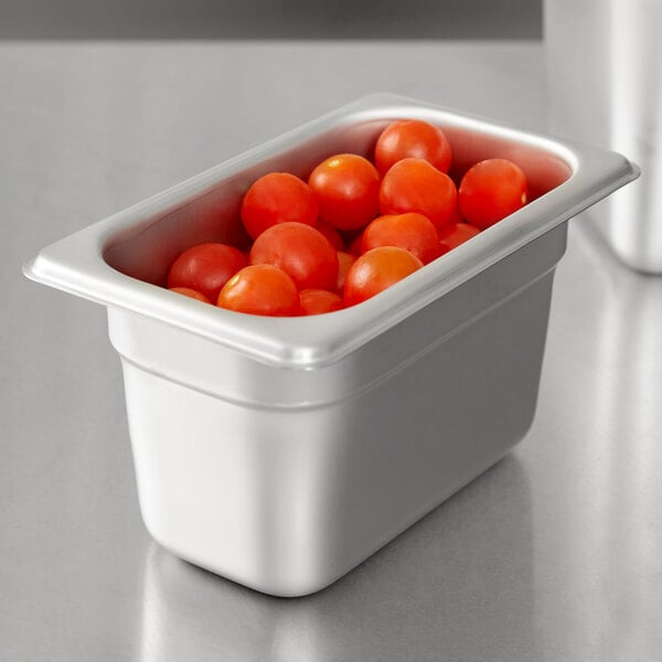 A stainless steel steam table pan with cherry tomatoes inside.