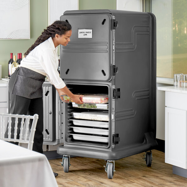 A woman using a Cambro Pro Cart Ultra to put food into a large metal container.