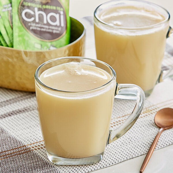 A box of David Rio Tortoise Green Tea Chai Latte single serve packets with a glass of chai latte.