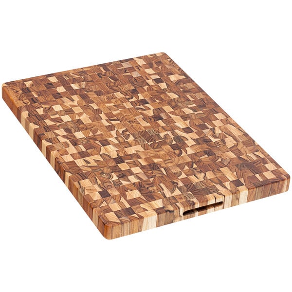 A Teakhaus End Grain Teakwood cutting board with hand grips on a table.