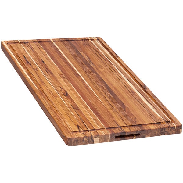A Teakhaus edge grain teakwood cutting board with hand grips.