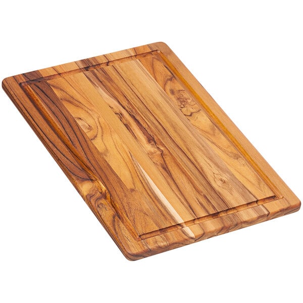 A Teakhaus edge grain teakwood cutting board with juice canal and wooden handle.