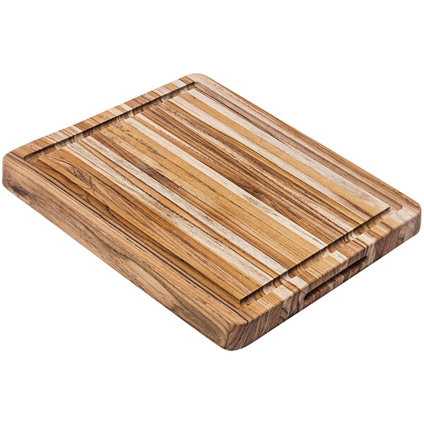 A Teakhaus teakwood cutting board with hand grips and a juice canal on a table.