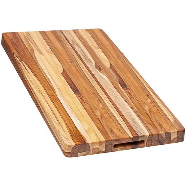 A Teakhaus edge grain teakwood cutting board with hand grips.