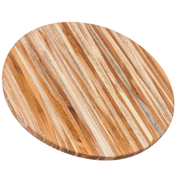 A Teakhaus round teakwood cutting board on a table.