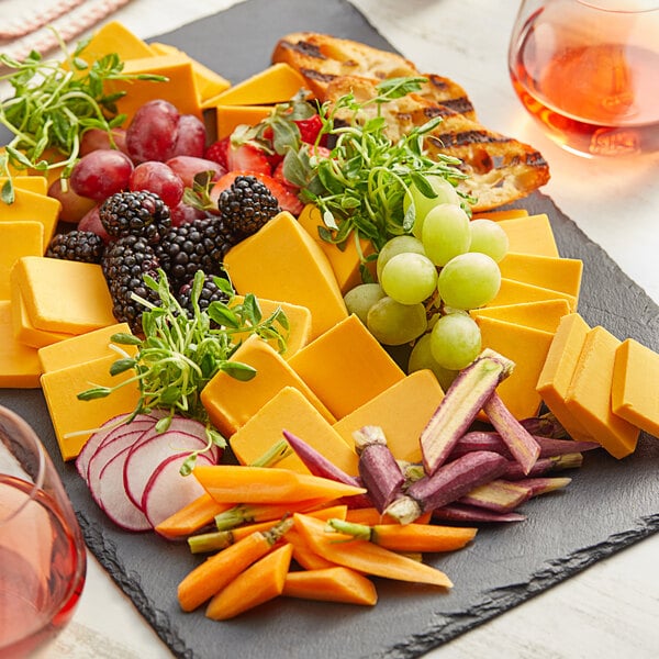 A plate of Daiya vegan cheddar cheese with grapes and carrots.