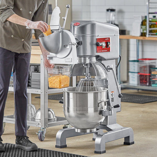 A man standing next to an Avantco 40 qt. floor mixer in a kitchen.