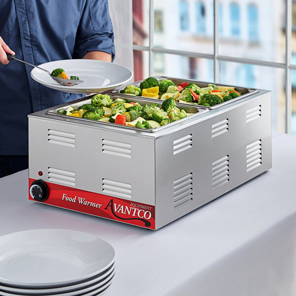 An Avantco countertop food warmer with a tray of food being served on a plate.