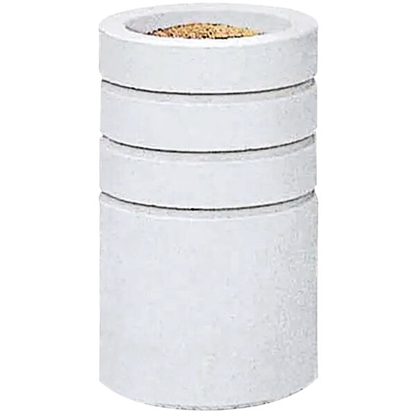 A white concrete cylinder with reveal lines filled with brown sand.