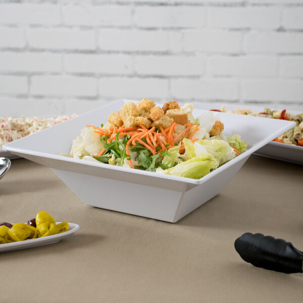 A white Siciliano square bowl filled with salad on a table.