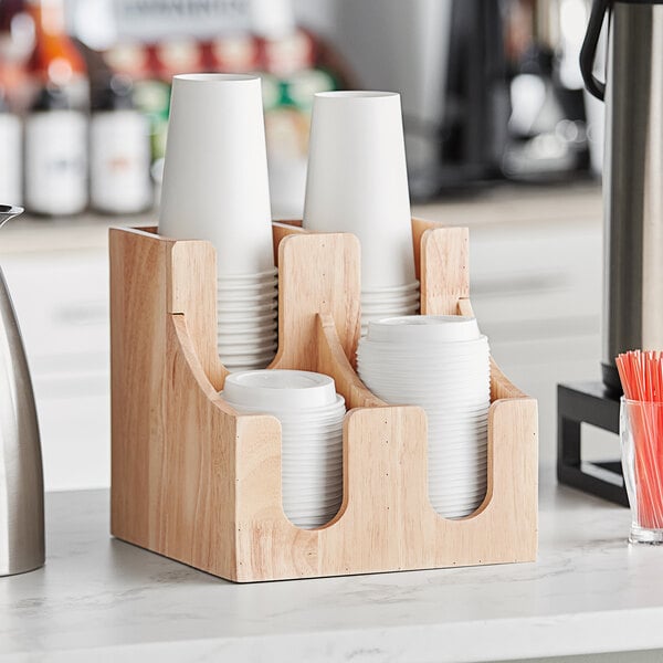 A wooden Acopa cup and lid organizer on a counter with cups.