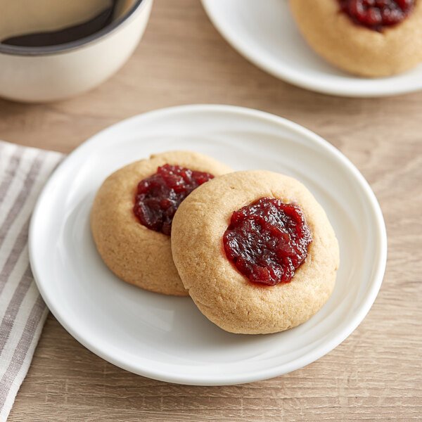 Two cookies with Ocean Spray Jellied Cranberry Sauce on top sit on a plate.