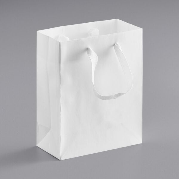 A white paper bag with ribbon handles.