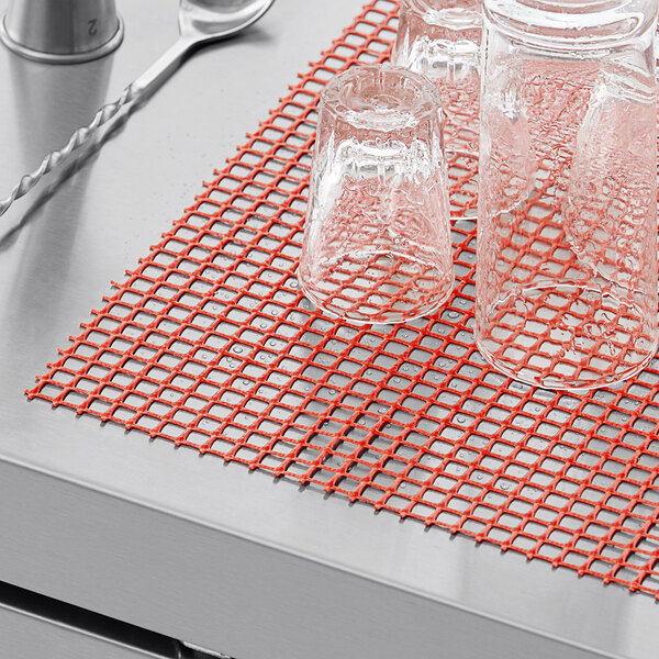 Red plastic mesh shelf liner on a counter with glasses.