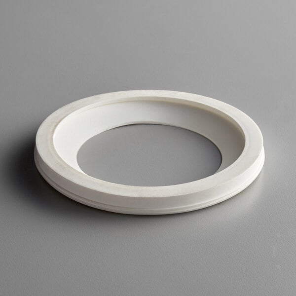 A white plastic bowl gasket with a white circle and a hole in it.