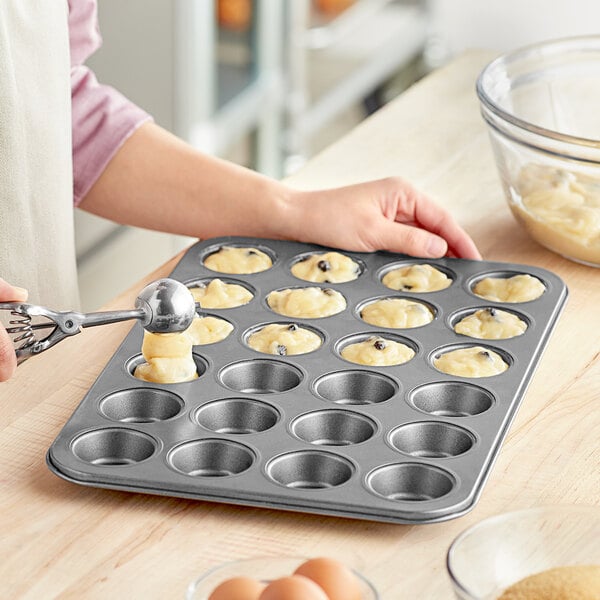 A woman using a Choice mini muffin pan to put food in.