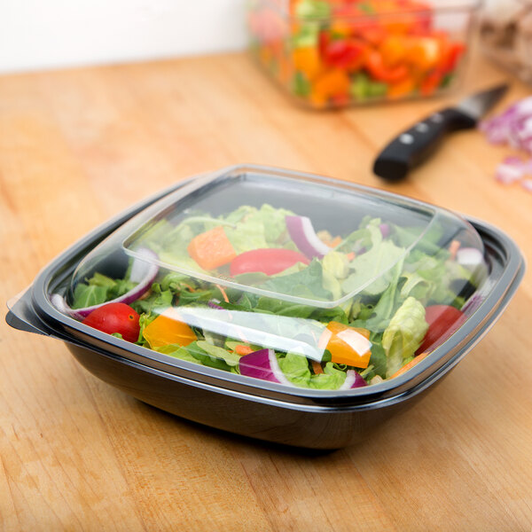 A clear plastic dome lid on a plastic container of salad.
