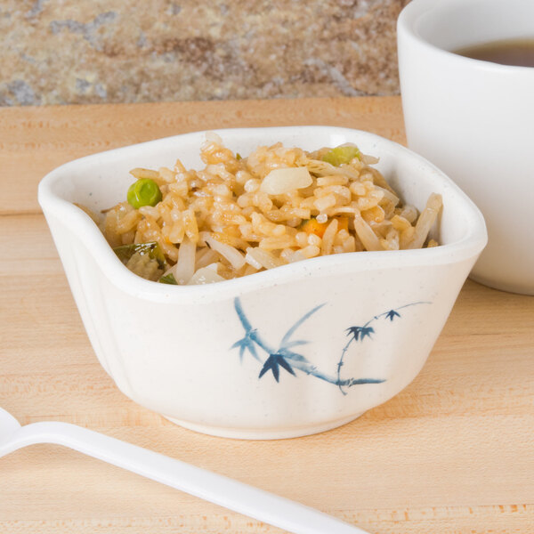 A bowl of rice and vegetables in a Thunder Group Blue Bamboo melamine dish on a wooden surface.