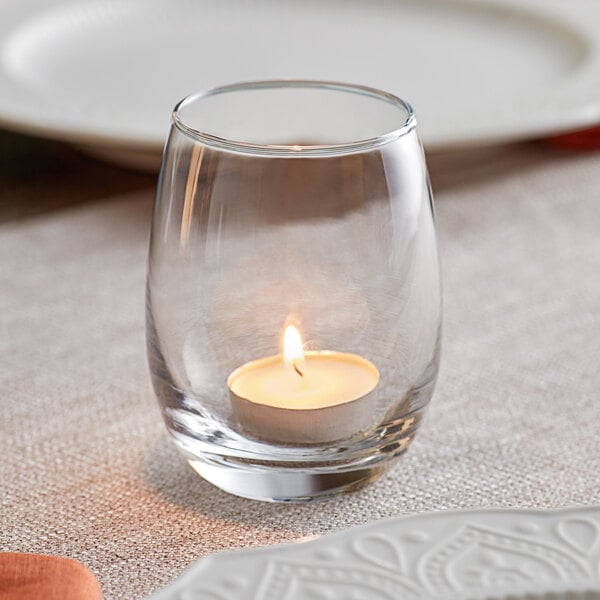 An Acopa bubble glass votive candle holder with a lit candle inside.