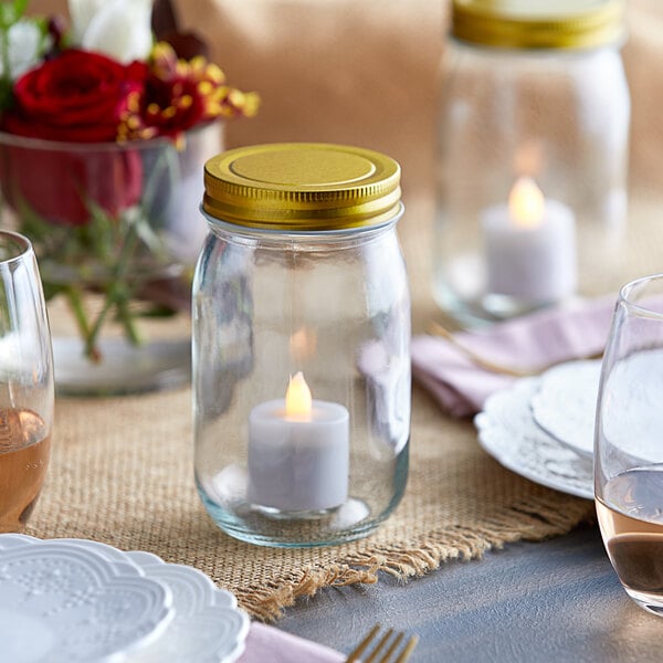 An Acopa mason jar with a lit candle inside on a table.