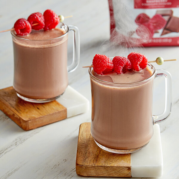 Two glass mugs of Land O Lakes Raspberry and Chocolate Cocoa with raspberries on top.