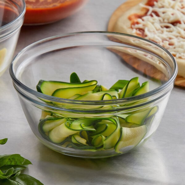 A glass bowl of cucumber slices on a counter.