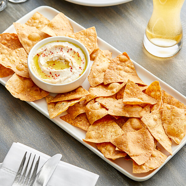 A plate of Mr. Tortilla Low Carb Black Truffle Crunchy Tortilla Chips with dip on a table in a farm-to-table restaurant.
