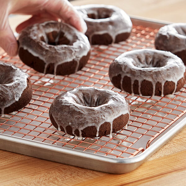A person holding a tray of Pillsbury chocolate donuts with icing.