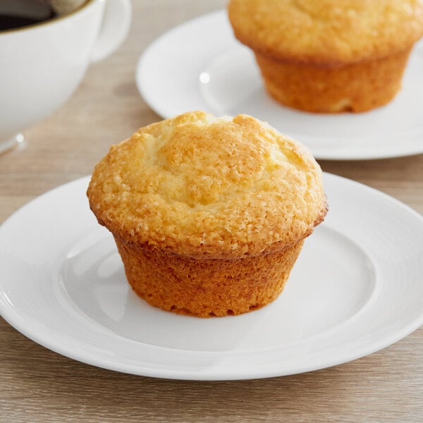 A muffin on a plate with a cup of coffee.