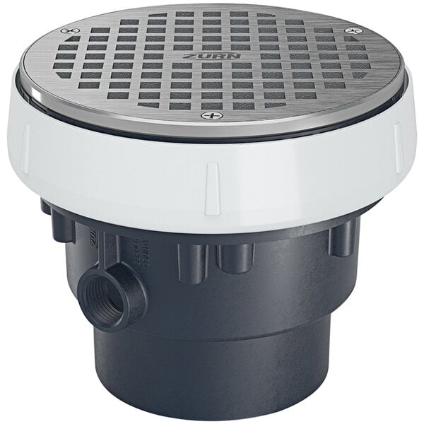 A Zurn nickel bronze floor drain strainer with a white circle around the edge over a round metal drain cover.