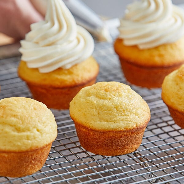 A close up of a group of yellow cupcakes with frosting on top of them.
