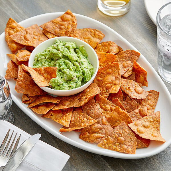 A plate of Mr. Tortilla Low Carb Spicy 3 Chiles Tortilla Chips with guacamole on a table in a Mexican restaurant.